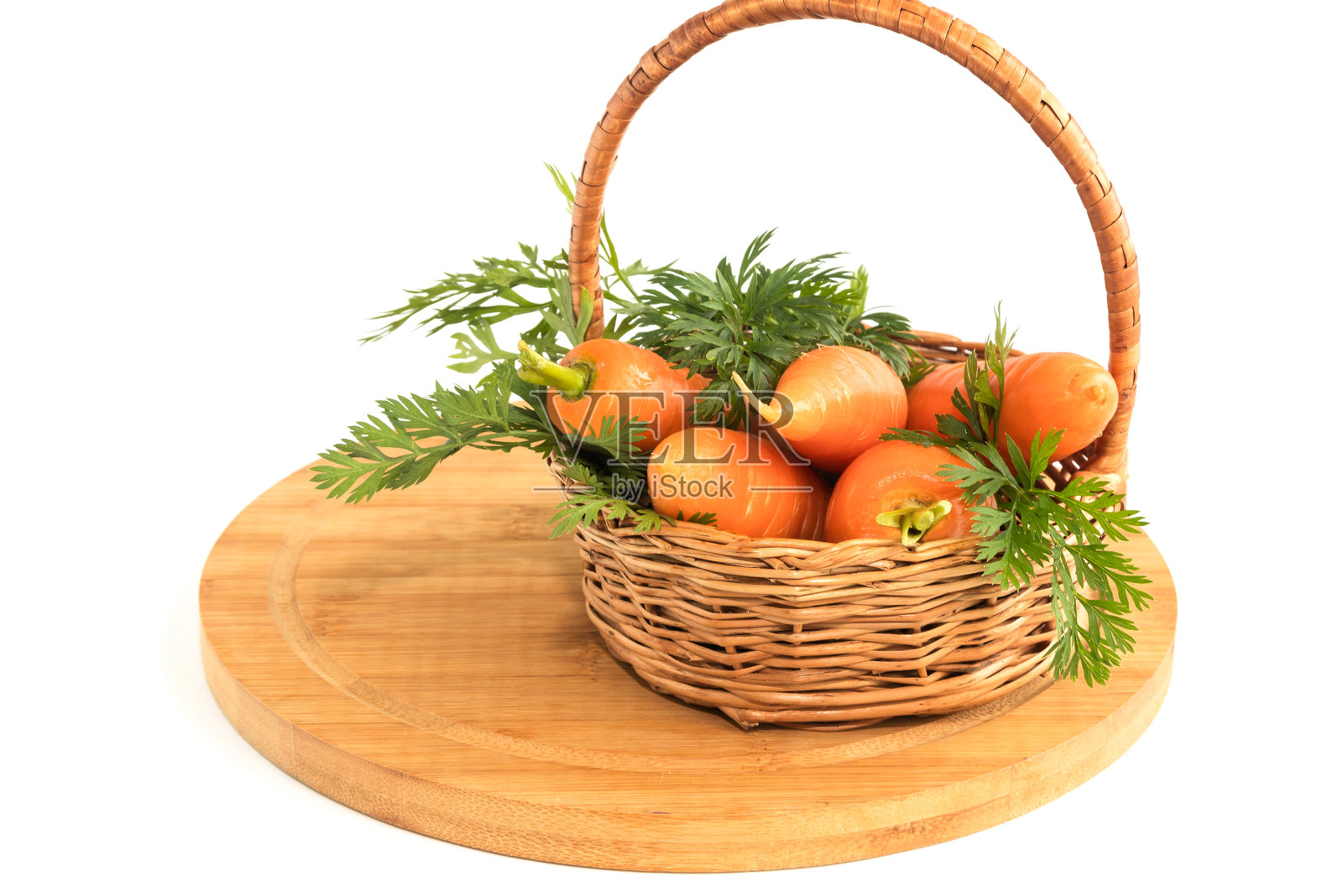 在一个小柳条篮子里，有绿色叶子的成熟新鲜的胡萝卜，孤立在白色的背景上。照片摄影图片