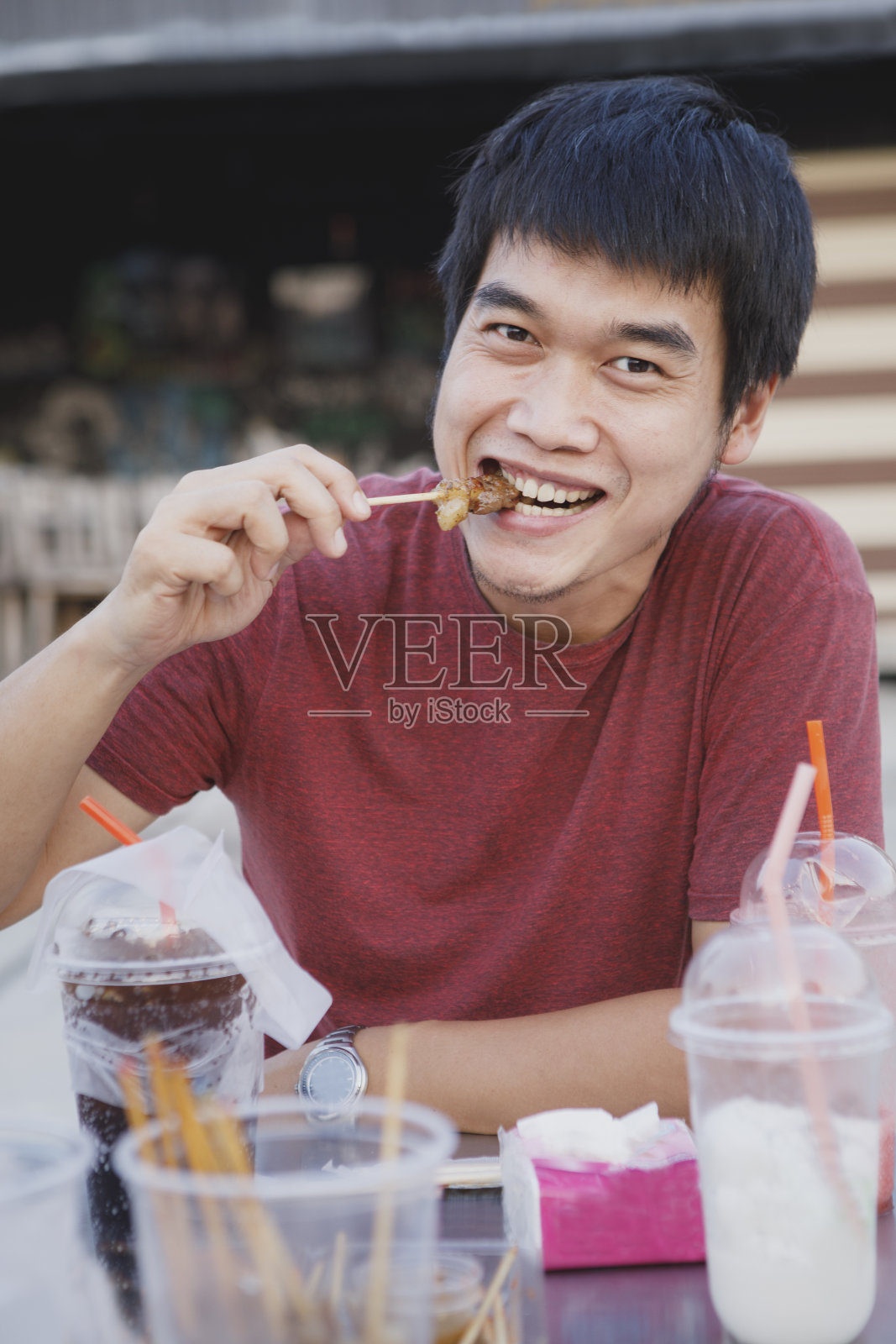 亚洲男人吃着一块烤牛肉，脸上挂着幸福的表情照片摄影图片