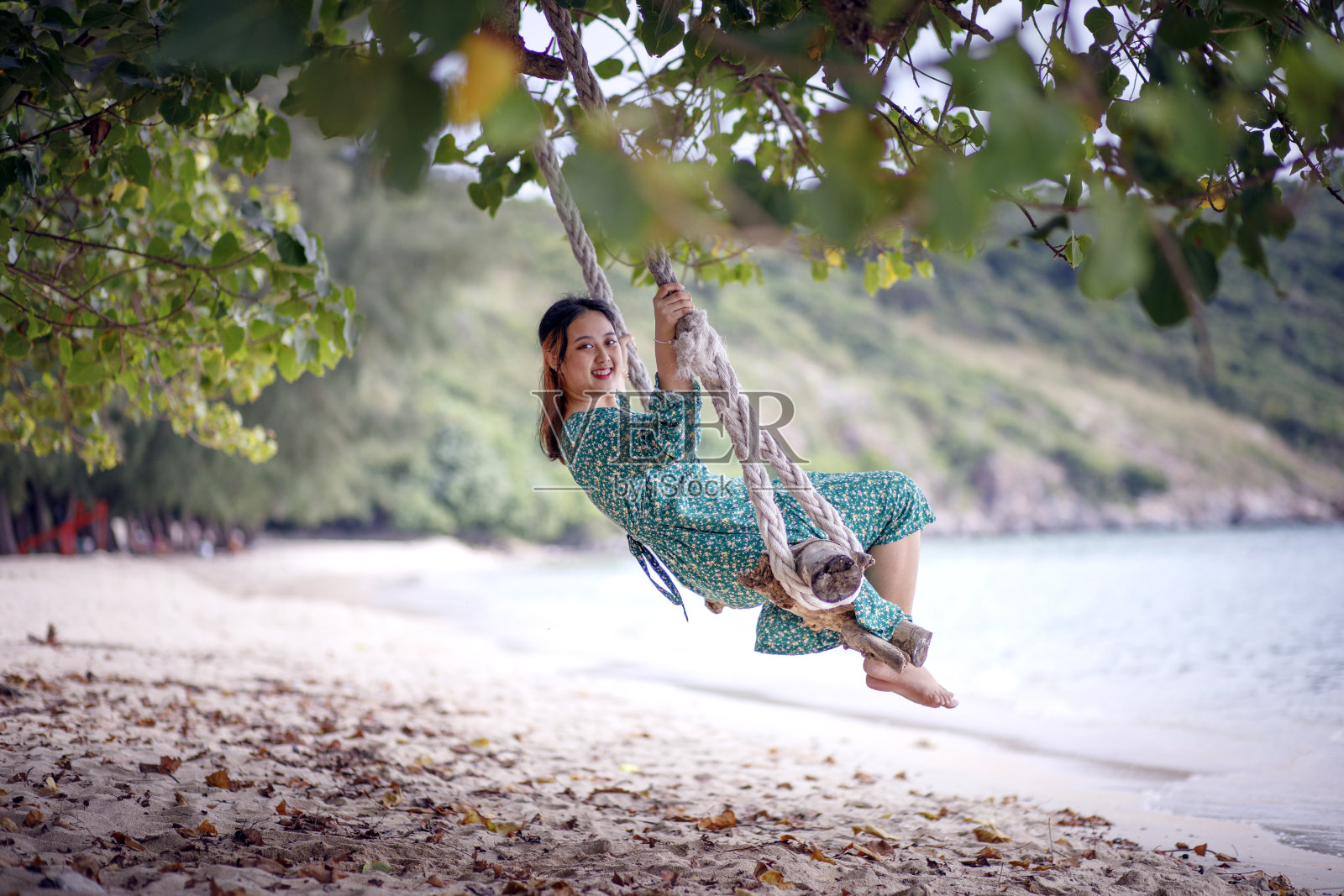 亚洲年轻女子放松在海滩秋千照片摄影图片