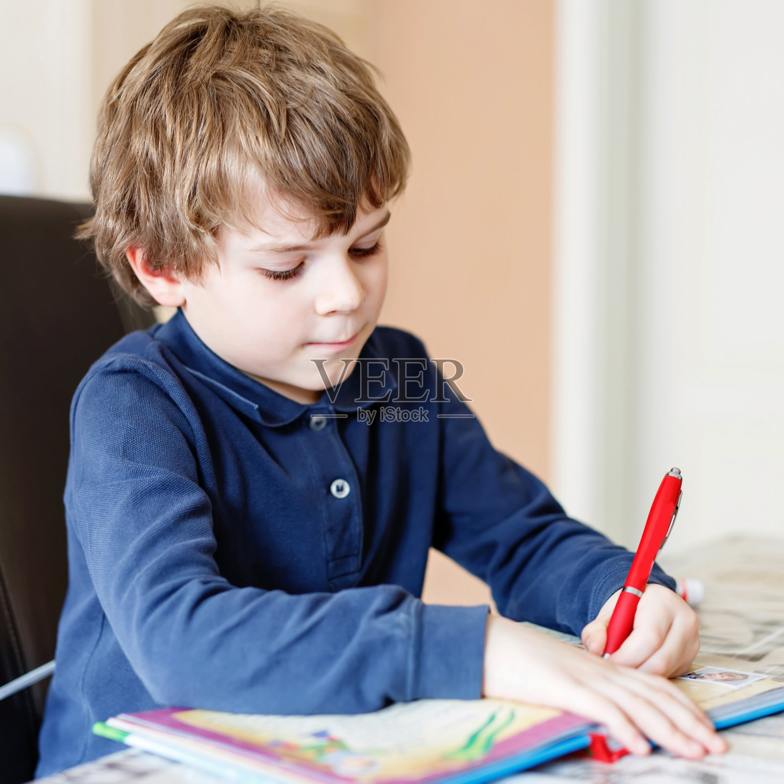 可爱的学龄前小男孩在家里做作业，用彩色笔写信。小孩子在室内用铅笔做运动。小学教育，幻想幻想概念照片摄影图片
