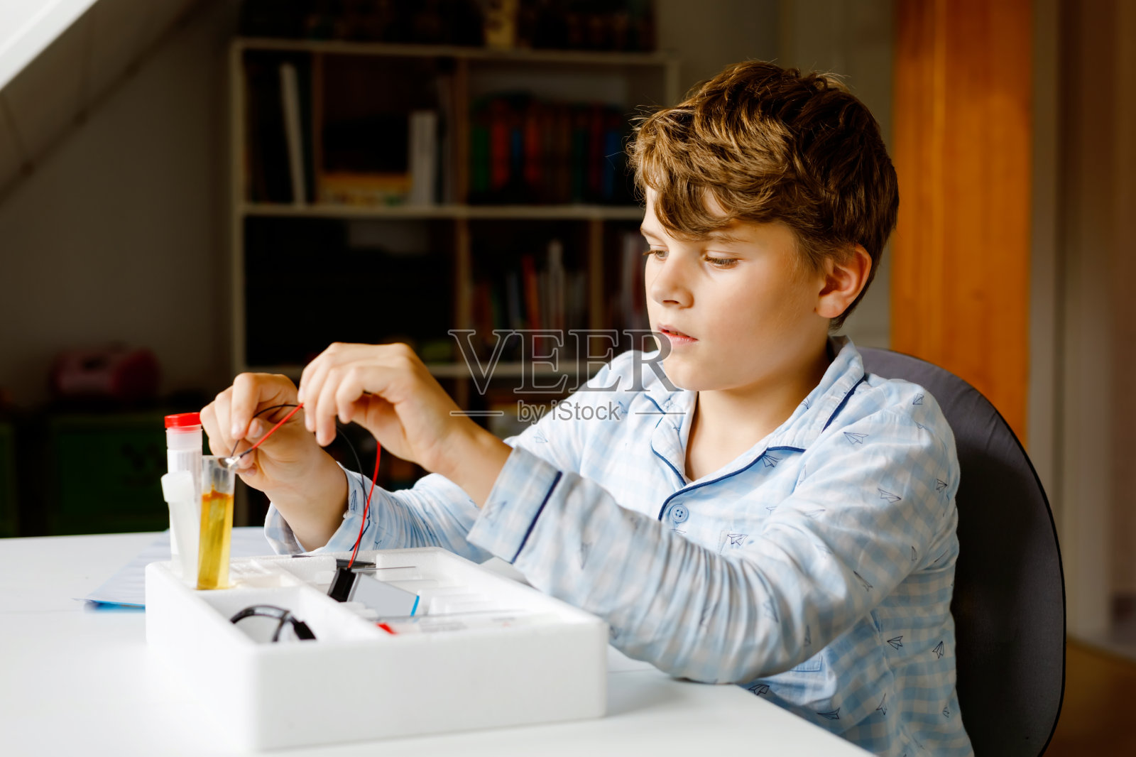 十几岁的小男孩在家做电子物理实验作为家庭作业。儿童研究电力。教育。孩子们学习物理。照片摄影图片