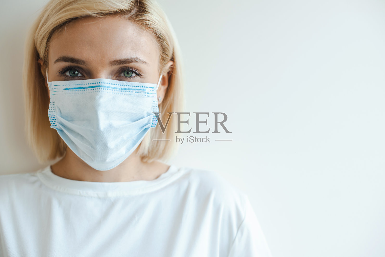 白色背景上一个戴着医用口罩的金发女人的肖像。病毒保护。本空间照片摄影图片