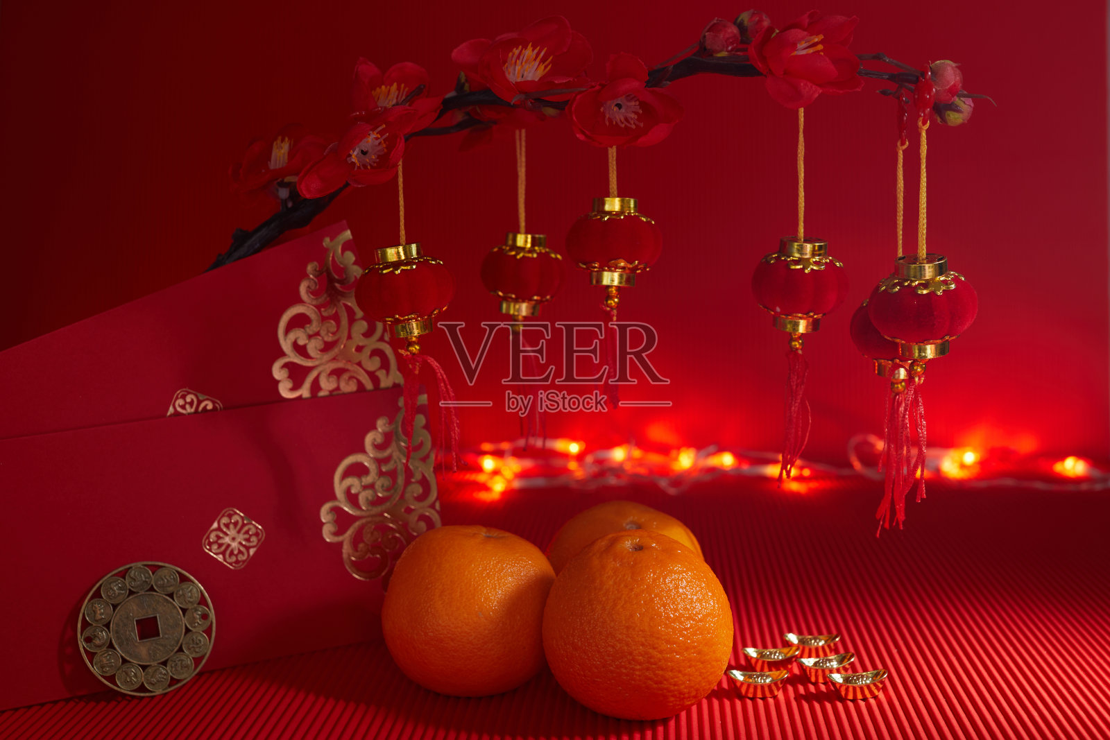春节节日装饰。橙色，叶子，红色的包，梅花在红色的背景上。照片摄影图片
