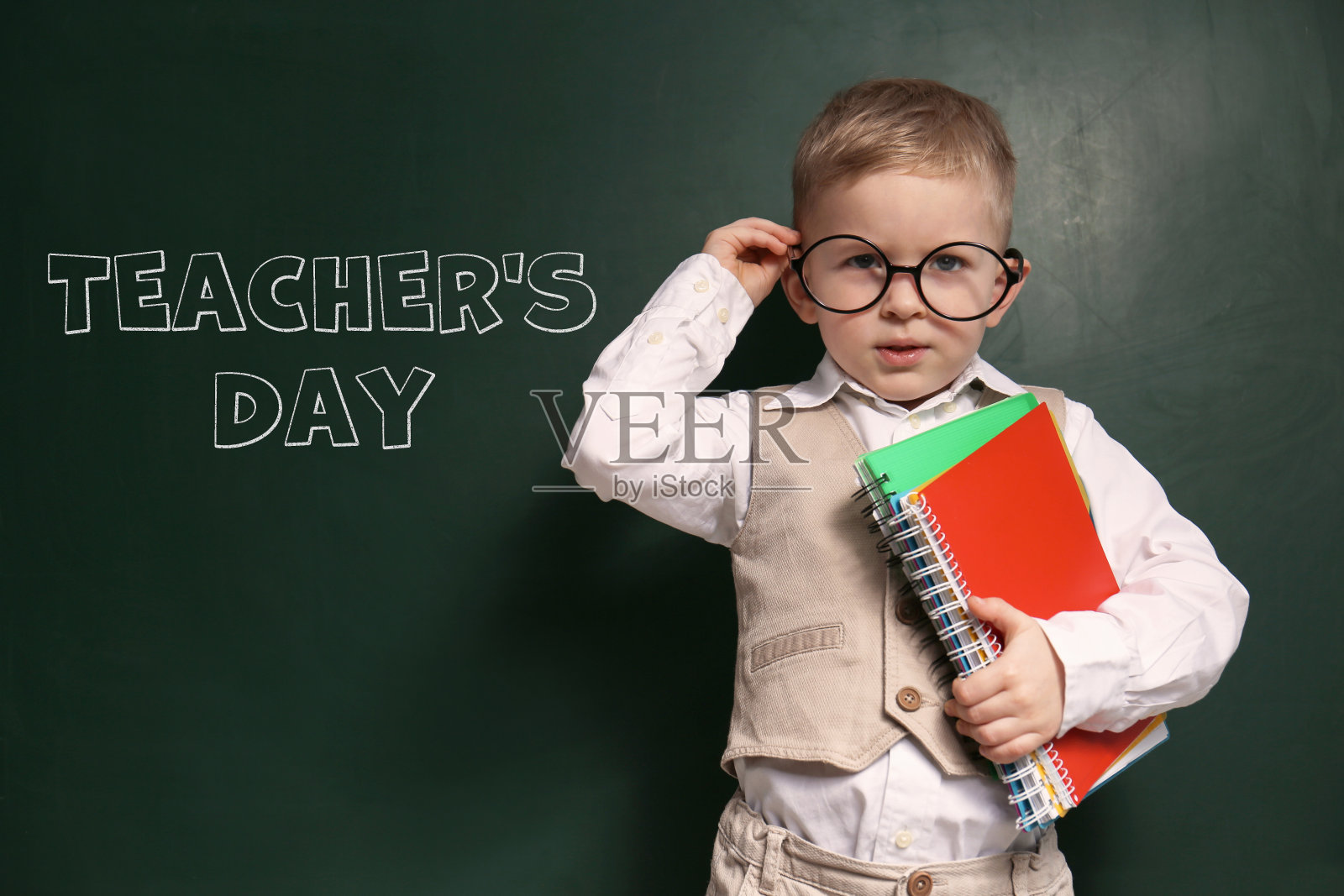 可爱的小男孩戴着眼镜靠近写有“教师节”字样的黑板照片摄影图片