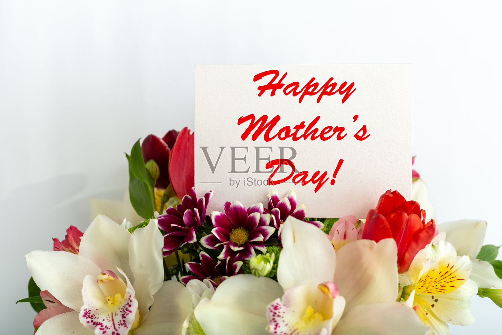 在白色背景的花束礼物卡片上母亲节快乐的文字。给妈妈的贺卡。送花，用鲜花包装的祝贺卡片送给女性。郁金香里的贺卡，兰花里的花束。照片摄影图片