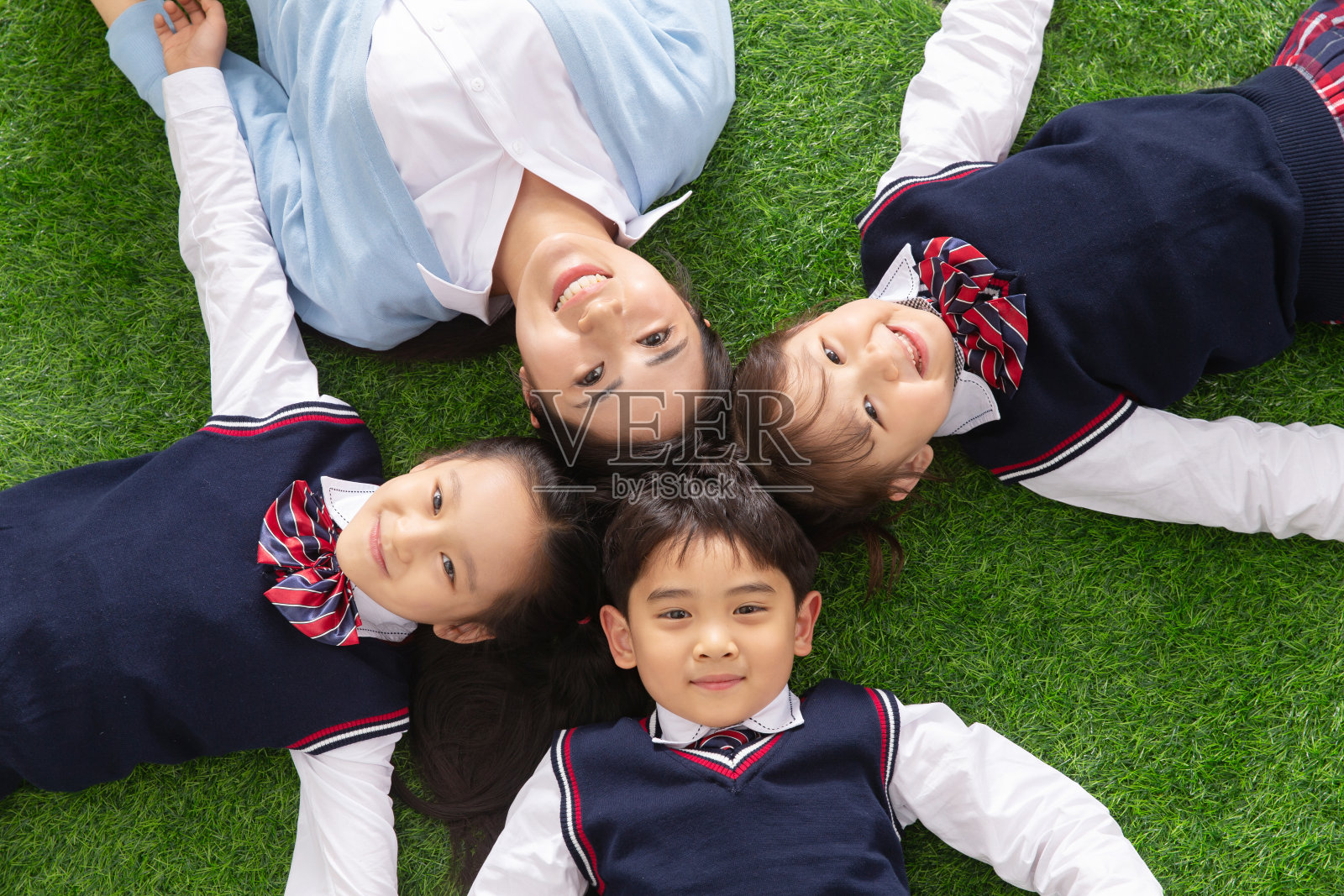 小学生们躺在草地上照片摄影图片