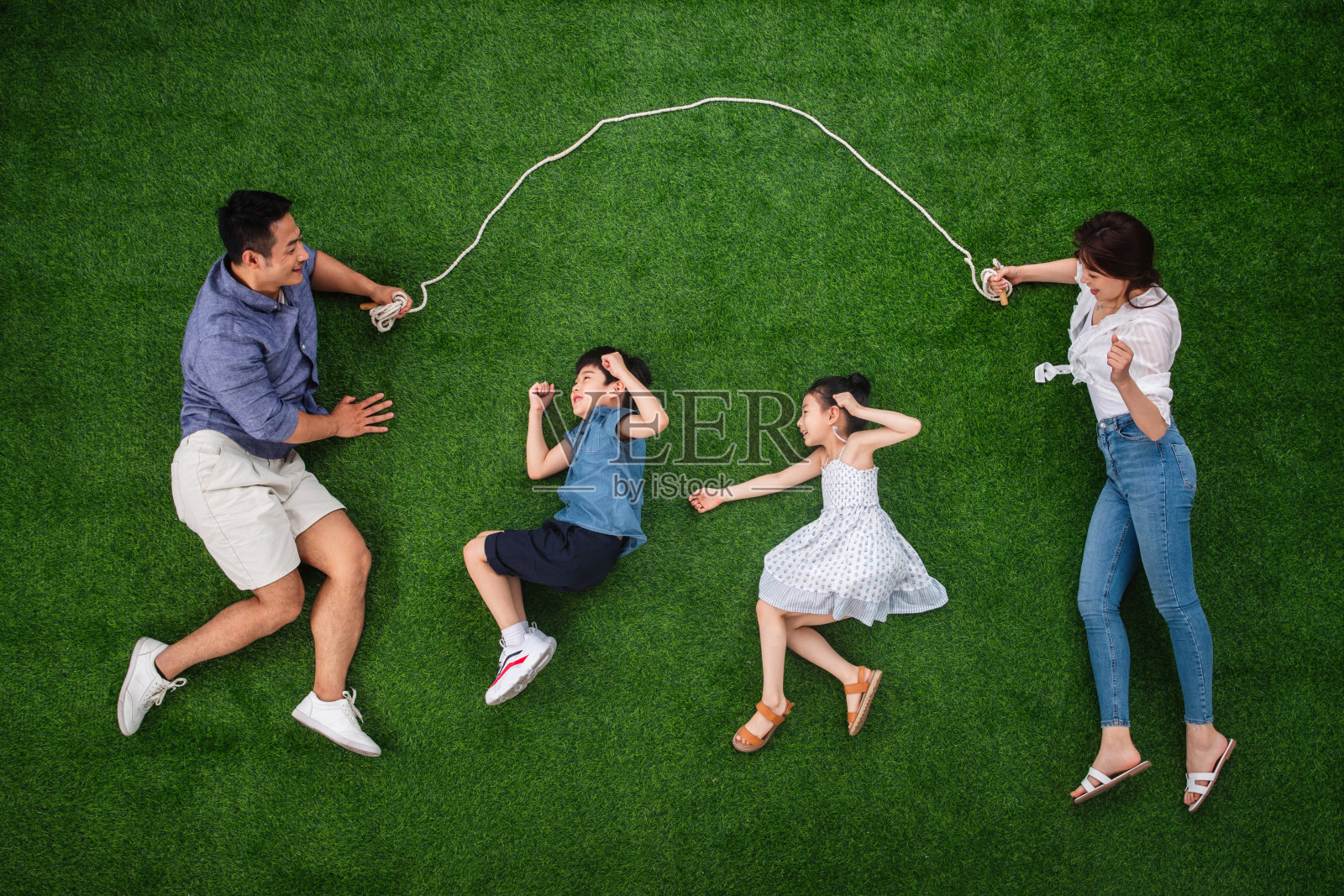 快乐的一家四口在草地上跳绳照片摄影图片