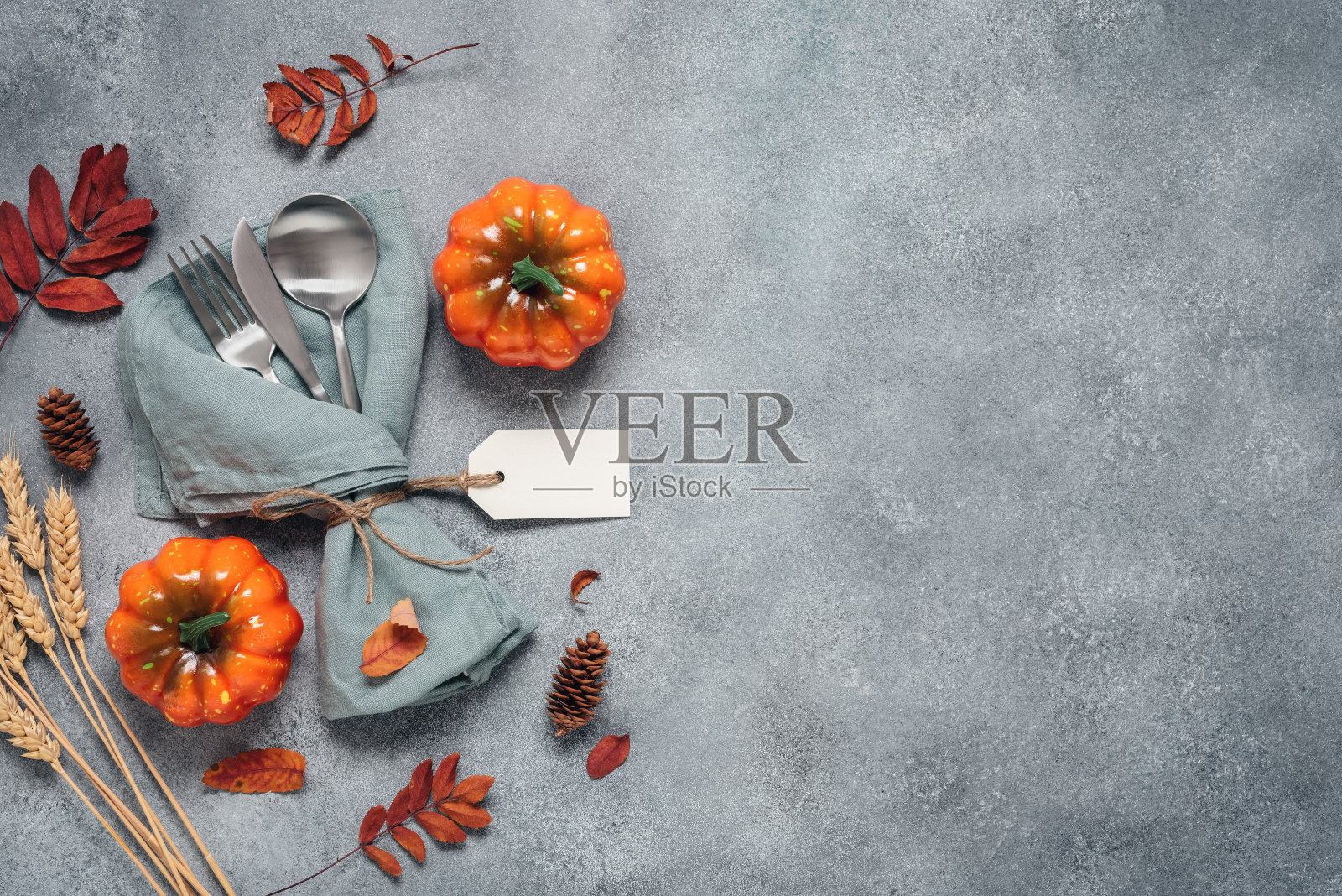 感恩节秋天的地方设置餐具，装饰南瓜和五颜六色的叶子。俯视图，平铺。,复制空间。有选择性的重点照片摄影图片