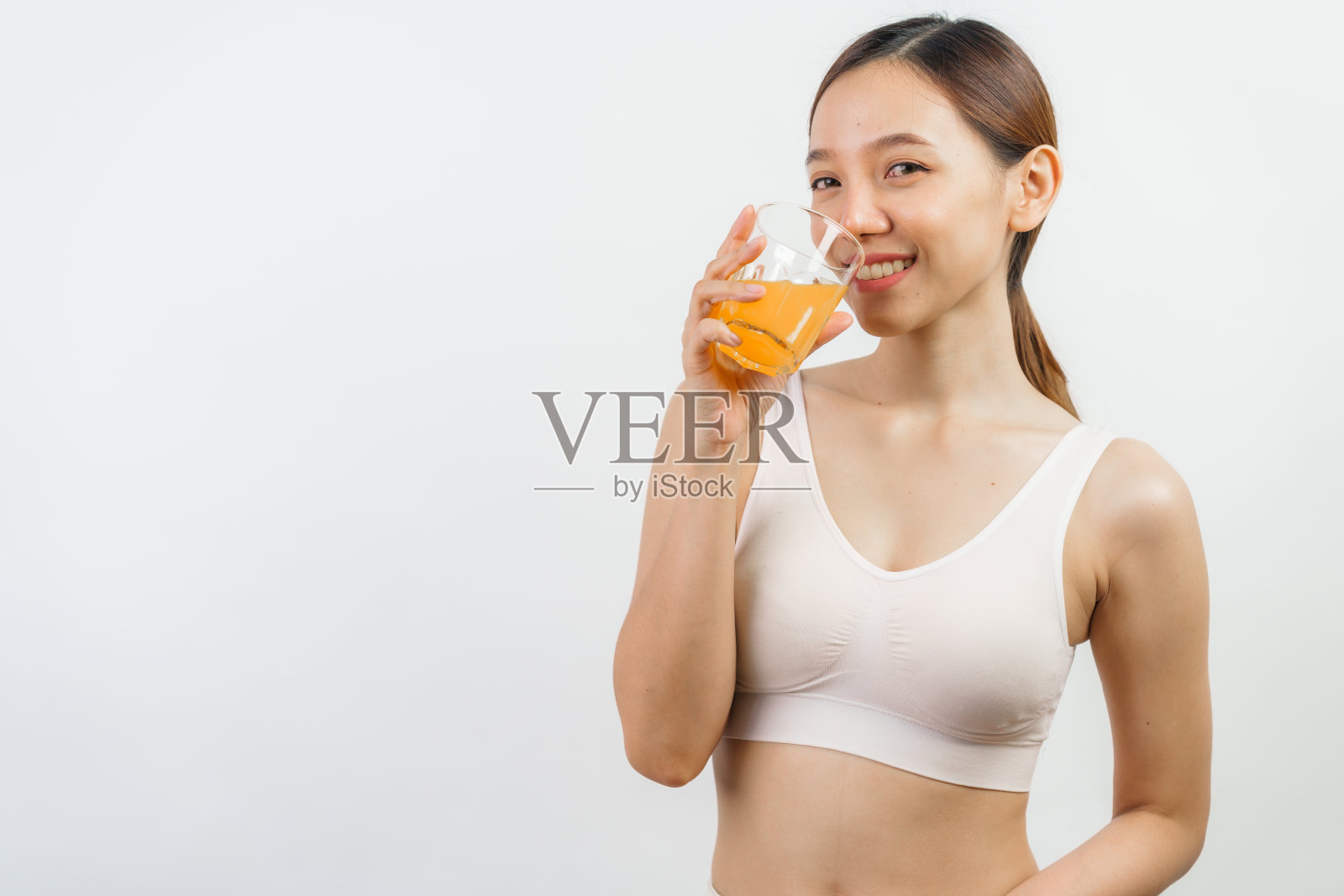 年轻漂亮的亚洲女子健康苗条喝橙汁，健康饮食理念，孤立于白色。照片摄影图片