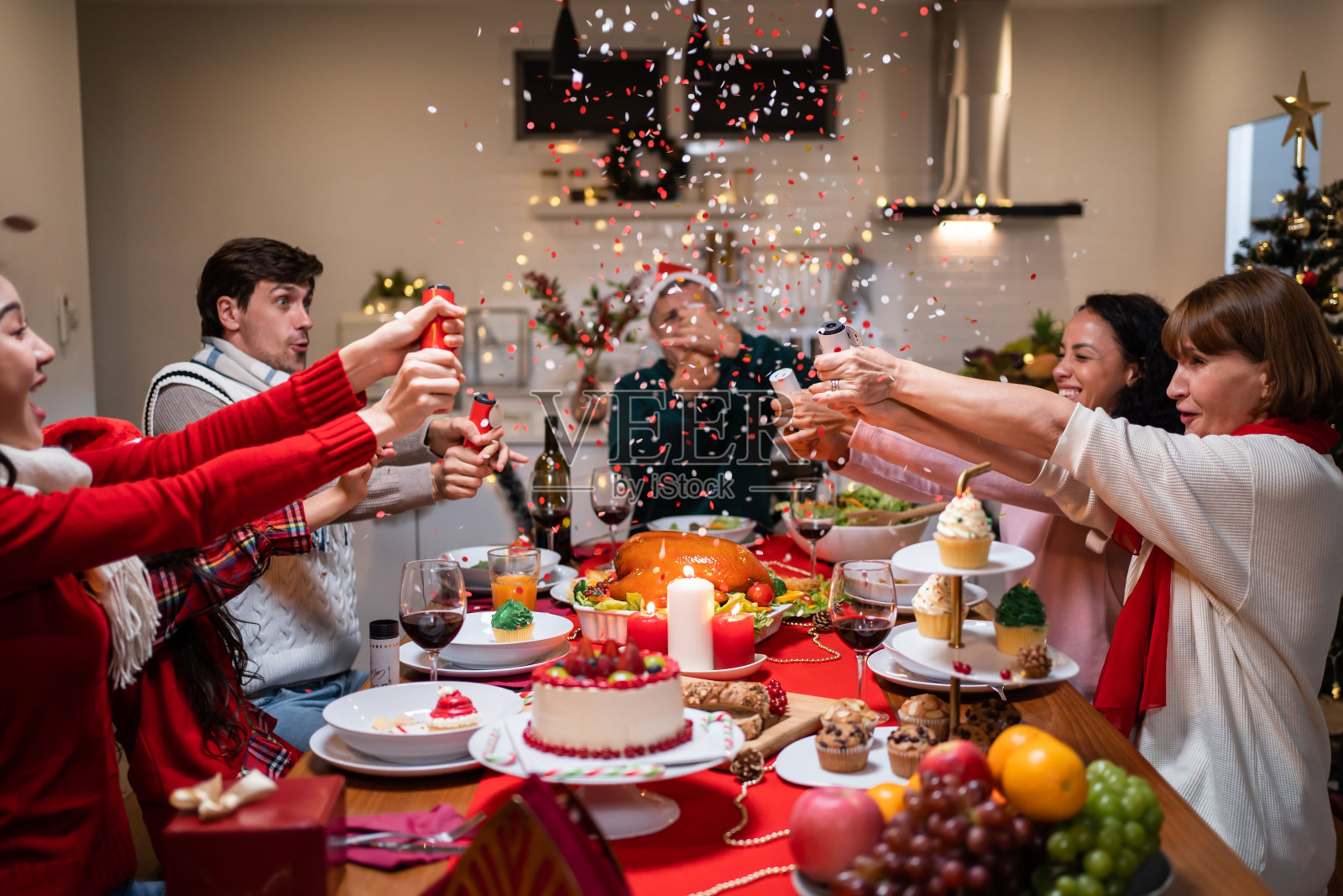 多民族大家庭在家里一起庆祝圣诞晚会。吸引形形色色的人们在餐桌上吃着美食，庆祝感恩节、圣诞夜的节日照片摄影图片