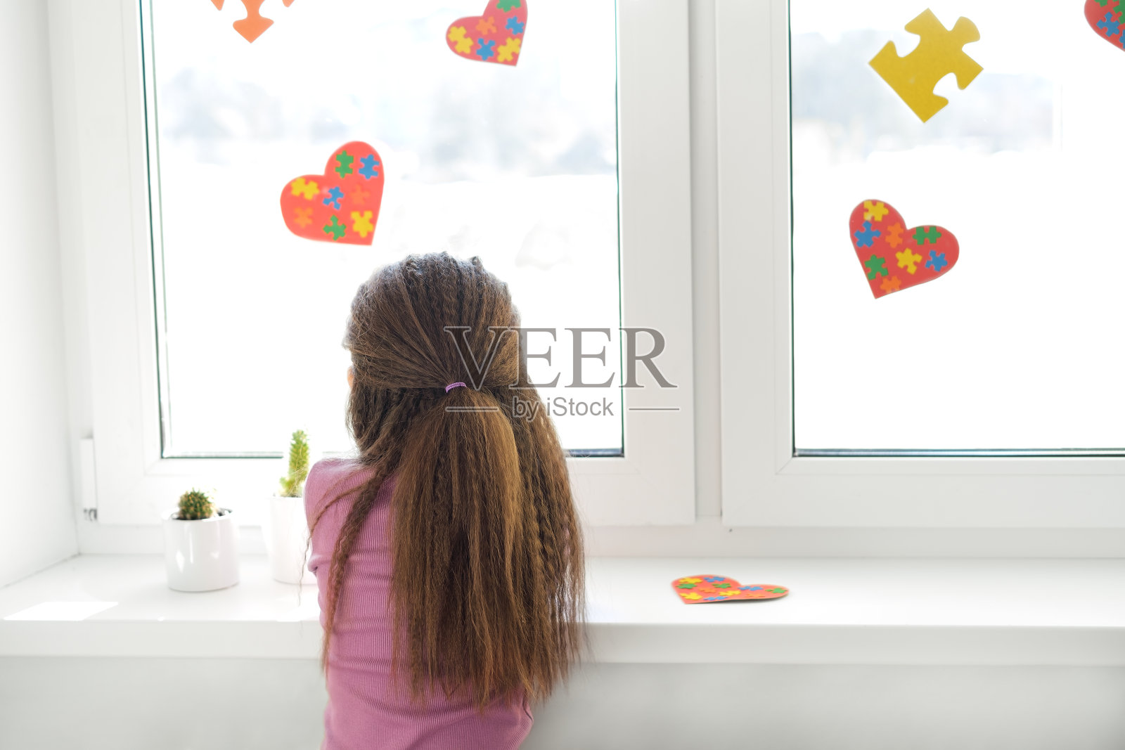 一个悲伤孤独的女孩看着窗外装饰着心形卡片照片摄影图片
