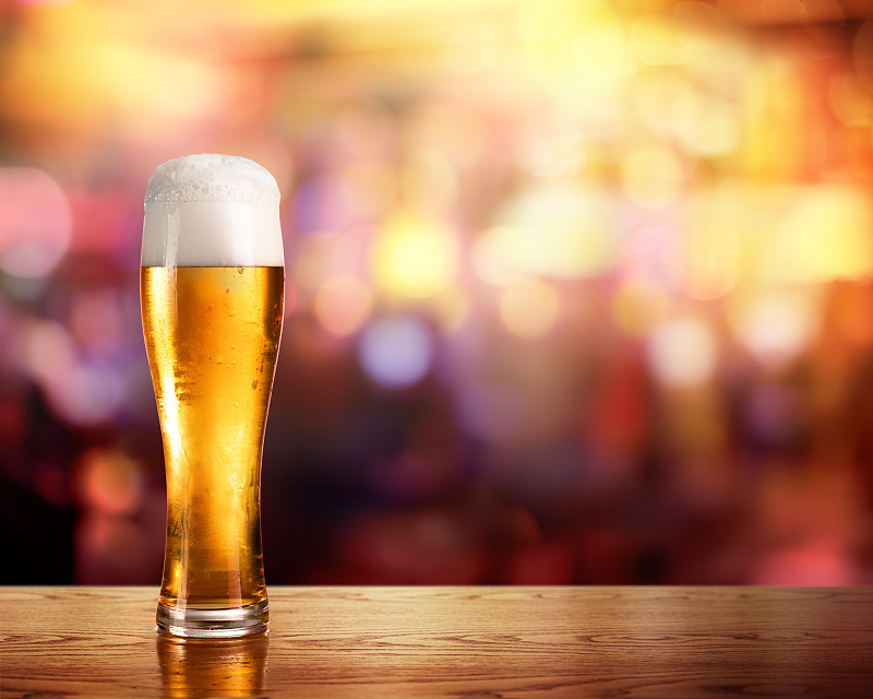 金色的啤酒在玻璃与酒吧的灯光在背景图片下载